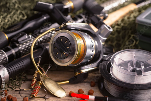 Fishing rods and spinnings in the composition with accessories for fishing on the old background on the table