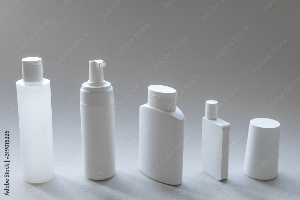 A line of white plastic cosmetic containers for body and face care with white space