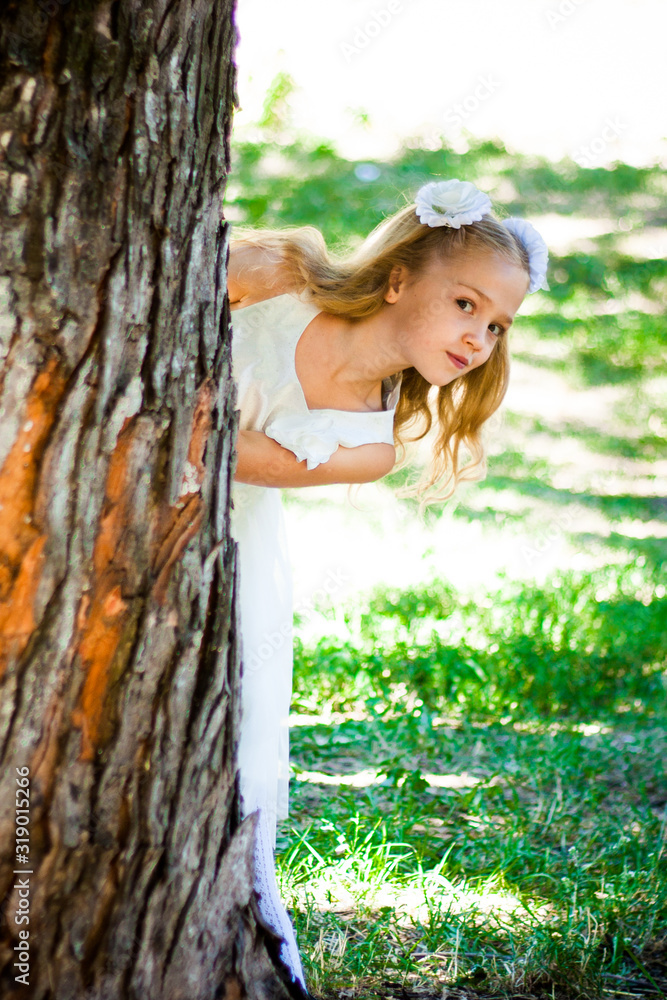 Naklejka premium Beautiful Girl Looks From The Tree In The Park. Warm sunny day