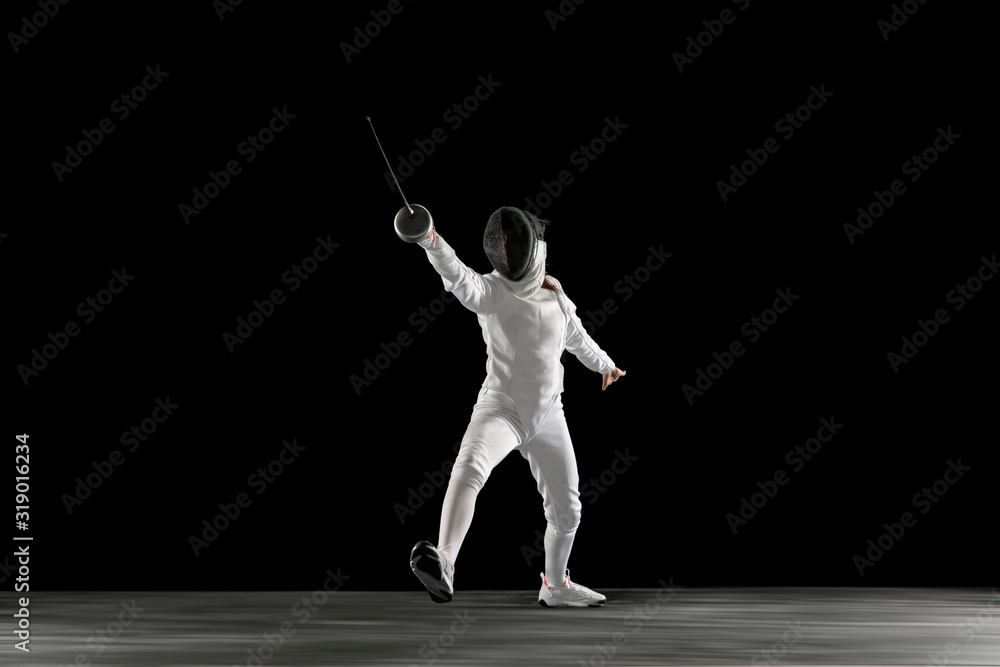 Targets. Teen girl in fencing costume with sword in hand isolated on black background. Young female model practicing and training in motion, action. Copyspace. Sport, youth, healthy lifestyle. Targets. Teen girl in fencing costume with sword in hand isolated on black background. Young female model practicing and training in motion, action. Copyspace. Sport, youth, healthy lifestyle.