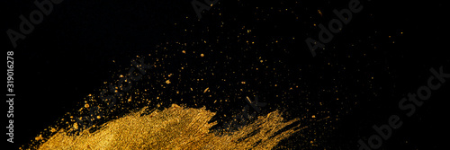 Golden stroke, drops and dots with acrylic paint and art brush on a black background.