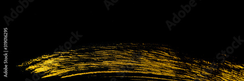 Golden stroke trace with acrylic paint by art brush on a black background.