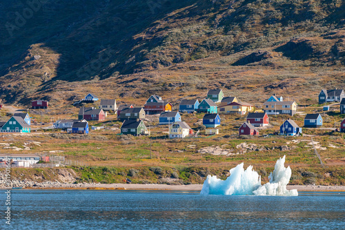View of a small Inuit village from the sea with floating icebergs.