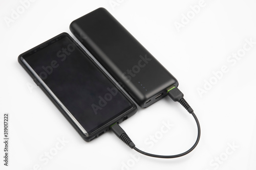 powerbank charges a smartphone battery on a white background. digital technologies and devices