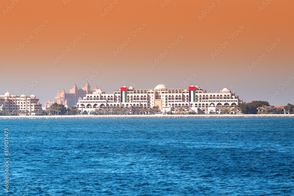 Hotel building with UAE flag on Palm Jumeirah Island in Dubai. Sea resort concept