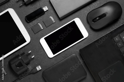 Electronic gadgets on a black concrete background. Concept of accessories for successful business. Flat lay.