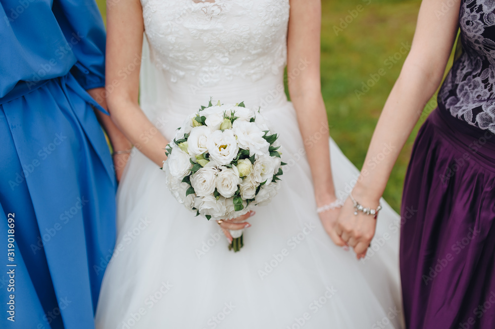 Bride and bridesmaids hold hands and hold a bouquet with white roses close-up. Photography, concept. Bride and bridesmaids hold hands and hold a bouquet with white roses close-up. Photography, concept.