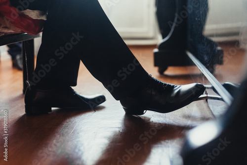 A male musician plays the piano, presses the foot in black shoes on the pedal close-up. Photography, concept. photo