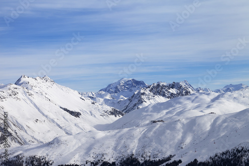 Snowy slope in high winter mountains and blue sunlit cloudy sky © BSANI