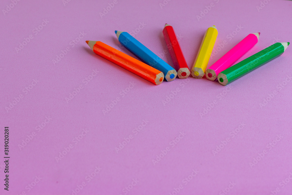 Colored pencils for drawing on a pink background. Copy space. Back to school backdrop. Kid's stationery. School supplies.
