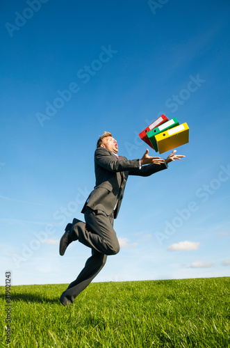 фотографія Clumsy businessman tripping dramatically with his file folders outdoors in a gre