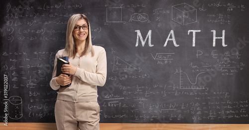 Young female teacher standing in front of a blackboard with text math