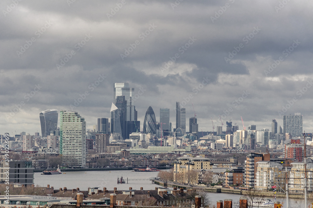 Panorama of London with the River Thames in the foreground and private buildings as well as office buildings and skyscrapers in the background during a cloudy day