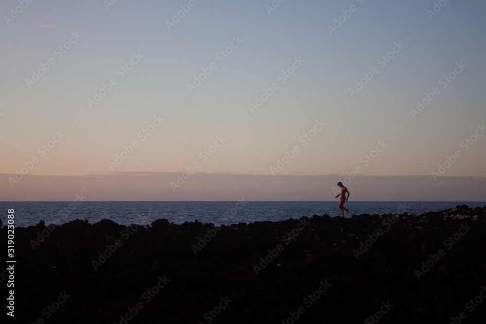 man walking on rocks by ocean