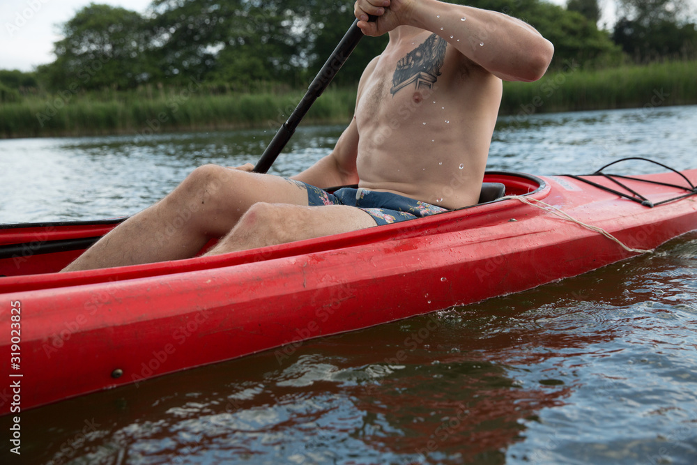 caucasian millennial man kayaking on river in the north during summer caucasian millennial man kayaking on river in the north during summer