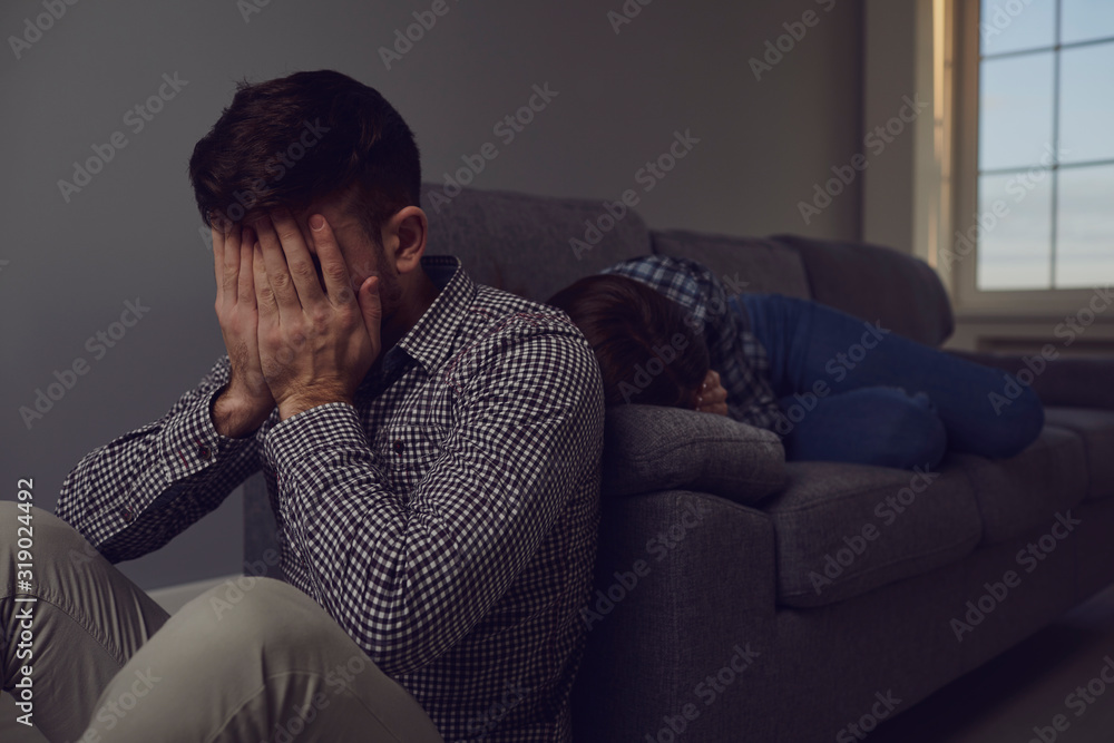 A young couple quarreling while sitting on a sofa in a room.