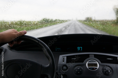car interior with drivers hand on the road on a track in rainy weather