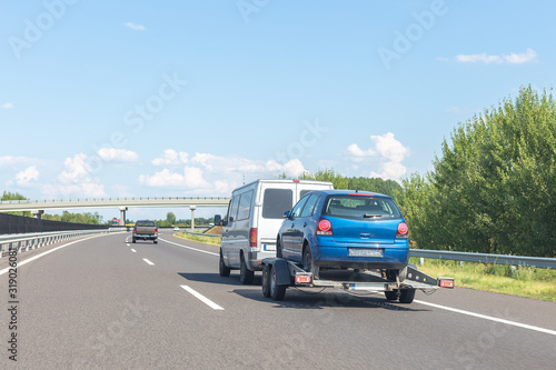 Car carrier trailer with blue car on highway