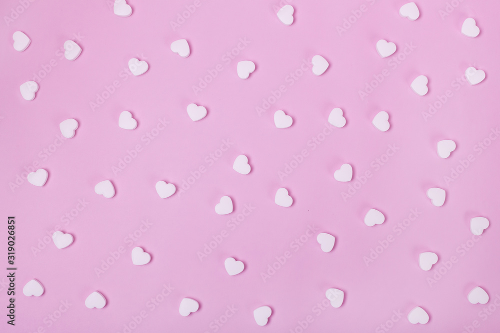White pills in the shape of a heart scattered on a pink pastel background. Medecine and placebo concept
