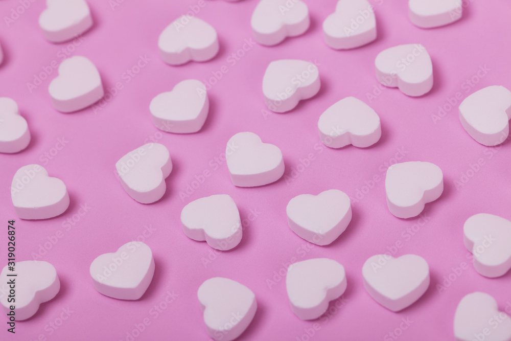White pills in the shape of a heart scattered on a pink pastel background. Medecine and placebo concept White pills in the shape of a heart scattered on a pink pastel background. Medecine and placebo concept