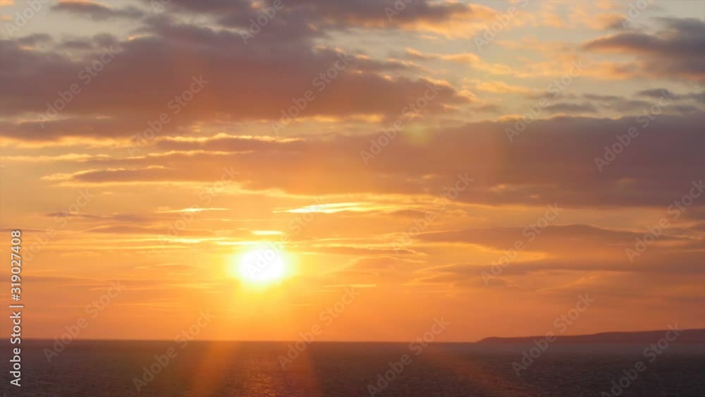 beautiful sunset on the background of sea, sun going beyond the horizon illuminating water and clouds in the sky beautiful sunset on the background of sea, sun going beyond the horizon illuminating water and clouds in the sky