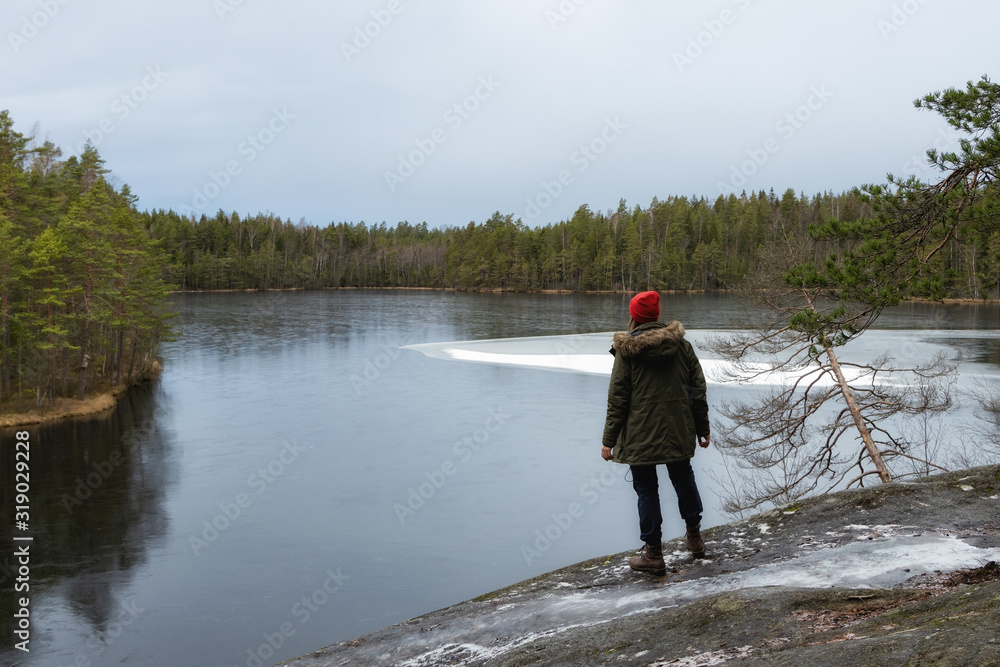 Traveler standing on rock. Cloudy dramatic winter sky. Cold weather, snowy lakesides with green fir forest. Travel concept. Traveler standing on rock. Cloudy dramatic winter sky. Cold weather, snowy lakesides with green fir forest. Travel concept.