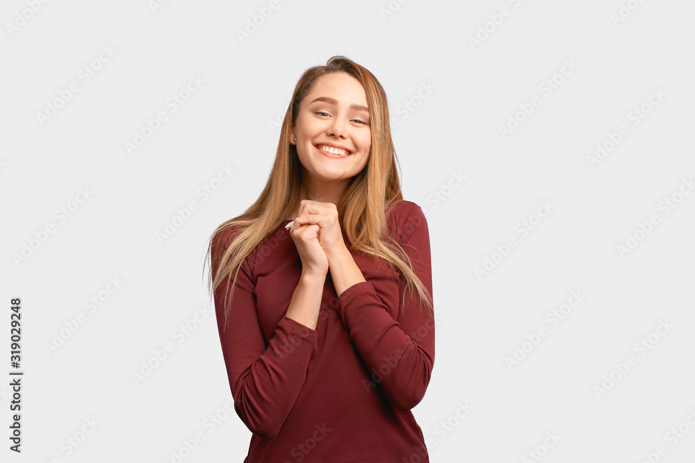 Cute girl squeezes hands together, shows gesture of thanks and gratitude. Beautiful young woman with long hair, clean smooth skin wears Burgundy-colored jacket sleeves isolated on white background Cute girl squeezes hands together, shows gesture of thanks and gratitude. Beautiful young woman with long hair, clean smooth skin wears Burgundy-colored jacket sleeves isolated on white background