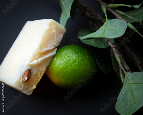 Slice of white handmade soap with almond seed and fresh green lime