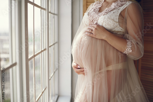 Pregnant woman. Blonde in a long pik dress. Woman with a big belly