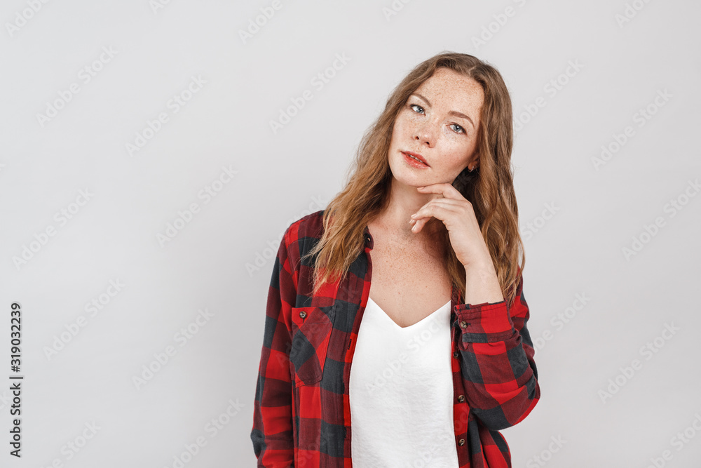 Freestyle. Young woman with freckles standing isolated on grey touching face tender posing sensual Freestyle. Young woman with freckles standing isolated on grey touching face tender posing sensual