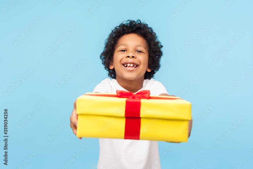 Φωτογραφία Take it! Full of joy amazing cute little boy with curly hair giving gift box to camera with excited smile, child greeting on holiday and sharing present
