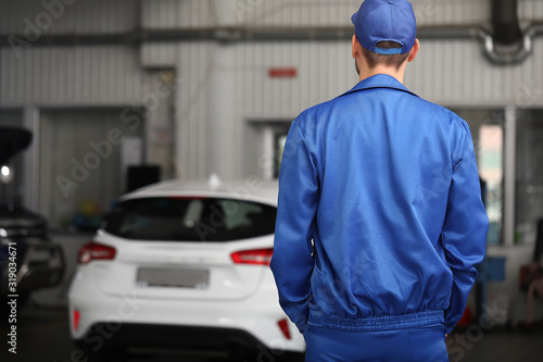 Male mechanic in car service center, back view