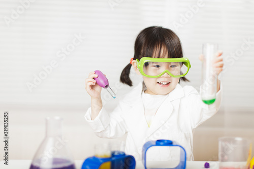 toddler girl pretend play scientist role at home against white background