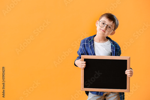 Little schoolboy with chalkboard on color background