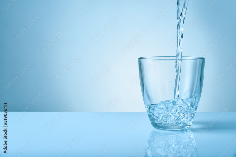 Pouring of fresh water into glass on color background Pouring of fresh water into glass on color background