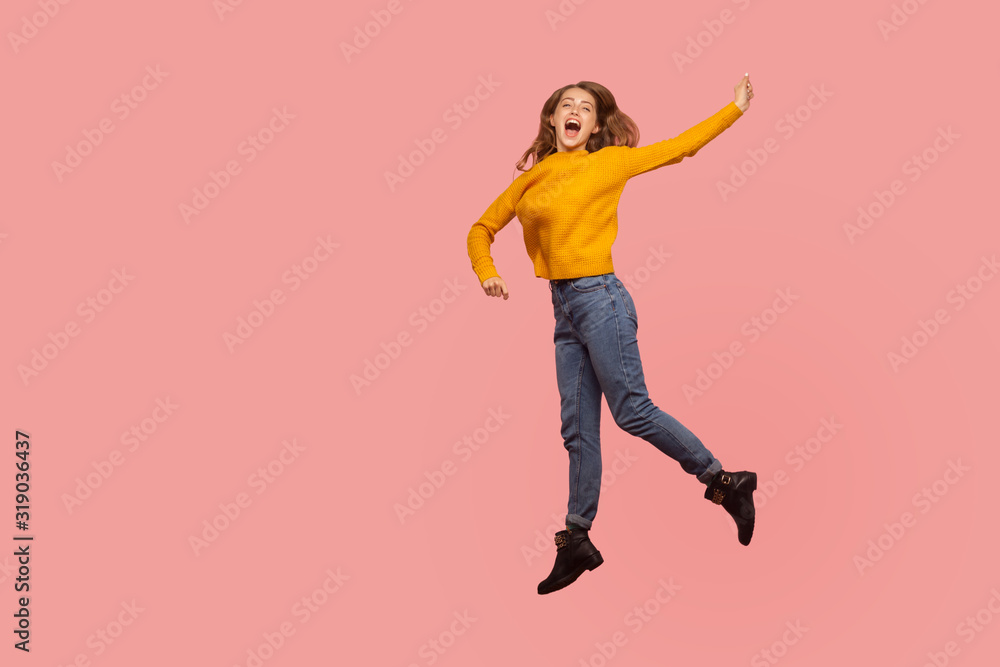 Φωτογραφία Portrait of lively energetic ginger girl in sweater and denim full of enthusiasm jumping in air or flying up, screaming from happiness