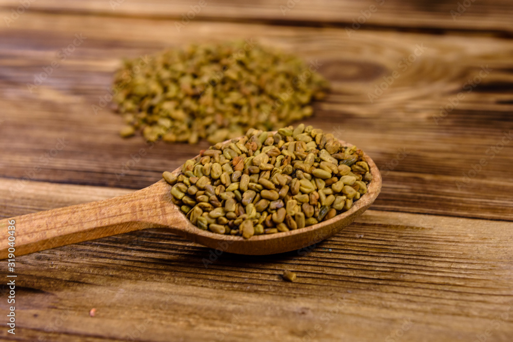 Spoon with fenugreek seeds on wooden table Spoon with fenugreek seeds on wooden table