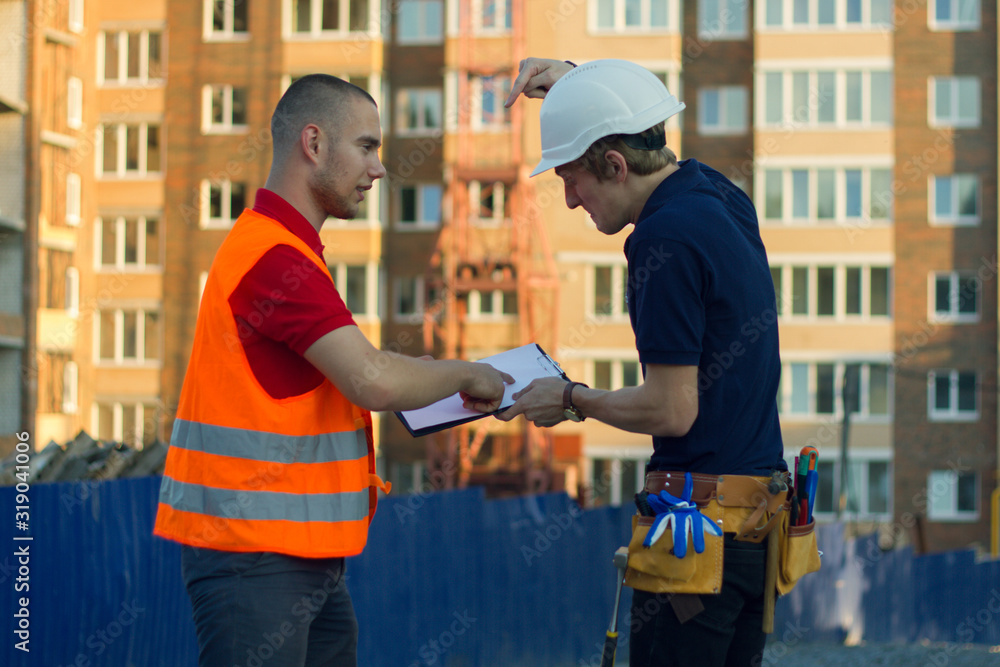 Fototapeta premium Two engineer builders with blueprint plan at construction site
