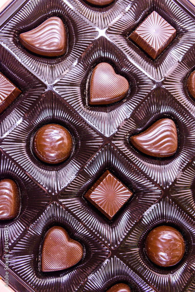 Fototapeta premium Heap of chocolate candies in a brown box. Top view