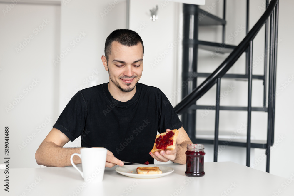 The guy has breakfast with toast with jam. The guy has breakfast with toast with jam.
