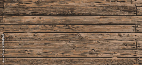 Rough stained neutral reclaimed wood surface with aged boards lined up. Wooden planks on a wall or floor with grain and texture. Dark vintage wood planks background.