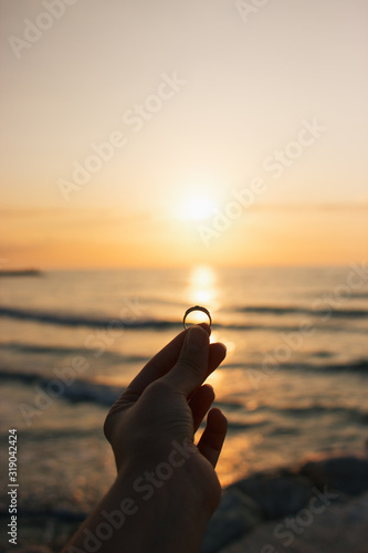 Woman holding the engagement ring in hand in the time sunrise on sea. An offer of marriage on beach of Italy. Film effect, author processing of photo © ksana_uk