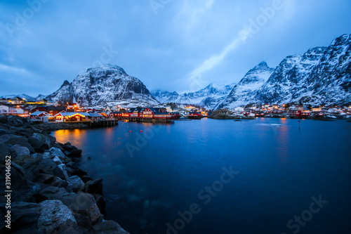 Panoramic overview of the small fishing village of A (Moskenes) at the end of the road of the Lofoten islands archipelago in northern Norway - Red rorbuer on stilts in winter at dawn in a fjord