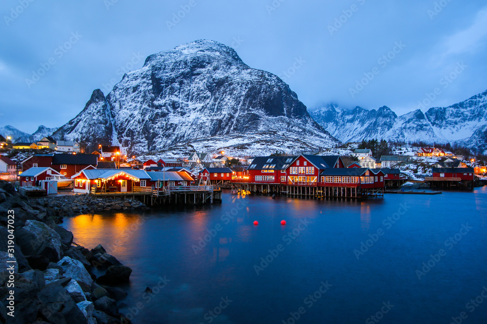 Small fishing village of A (Moskenes) at the end of the road of the Lofoten islands archipelago in northern Norway - Red rorbuer on stilts in winter at dawn