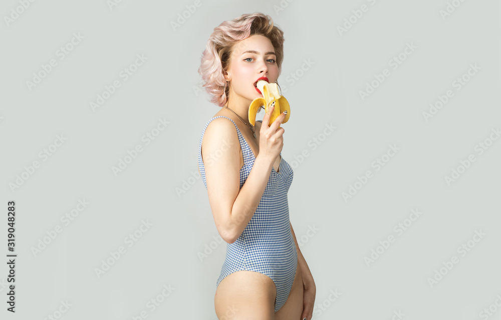 Cute girl eating a banana. Beautiful young woman in blue beachwear. Perfect body. Fashion portrait of beautiful girl with short wavy blonde hair. Sexy fashionable girl summer swimsuit. Cute girl eating a banana. Beautiful young woman in blue beachwear. Perfect body. Fashion portrait of beautiful girl with short wavy blonde hair. Sexy fashionable girl summer swimsuit.