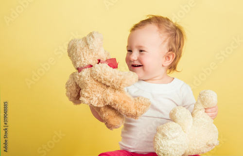 Caucasian little girl, children isolated on yellow studio background. Portrait of cute and adorable kid, baby playing with teddy bears. Concept of childhood, family, happiness, new life, education.