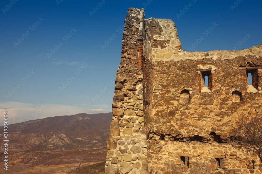 Georgian Culture, Travel concept. Old wall of Jvari monastery complex  near Mtskheta, Georgia. Sunny weather, blue sky with clouds. Text space. Outdoor shot