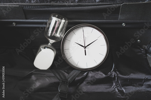 time to travel or delay during a trip, empty suitcase with clock and hourglass in it