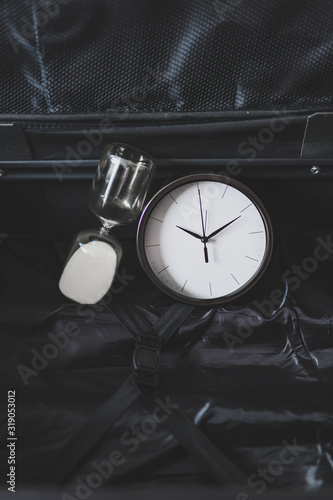 time to travel or delay during a trip, empty suitcase with clock and hourglass in it