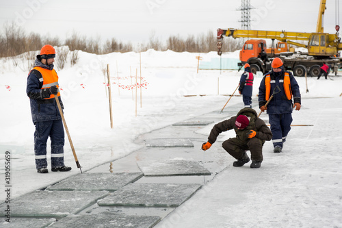 Worker measures the thickness of the ice in the pond